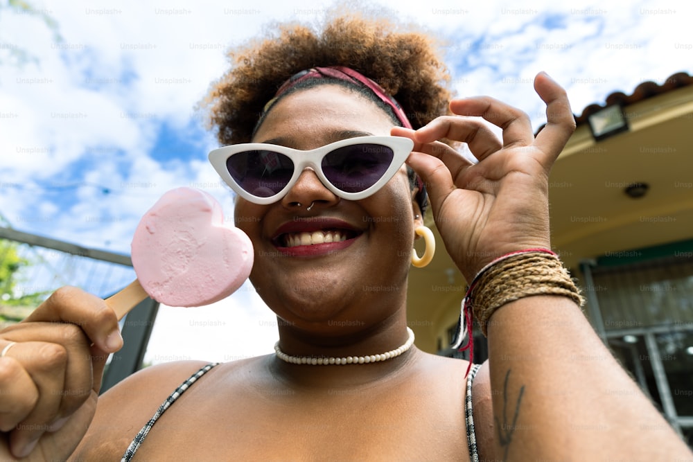 a woman wearing sunglasses and holding a lollipop