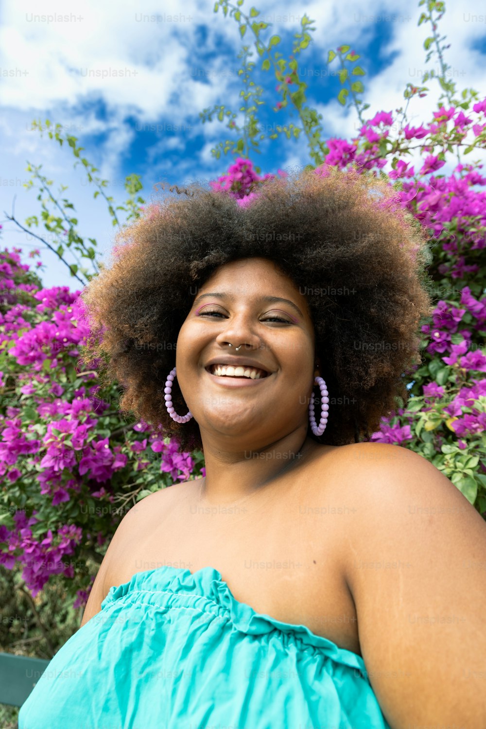 Una mujer con una sonrisa afro frente a flores moradas
