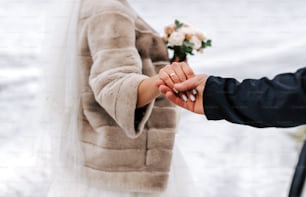 a bride and groom holding hands in the snow