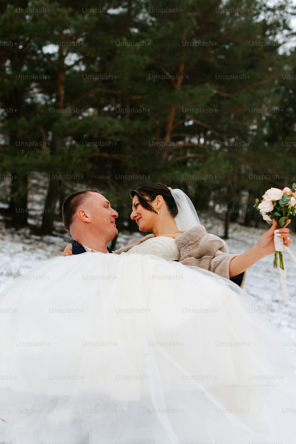 a bride and groom are sitting in the snow