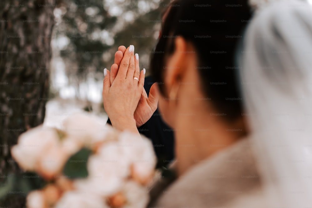 une femme en robe de mariée tenant ses mains jointes
