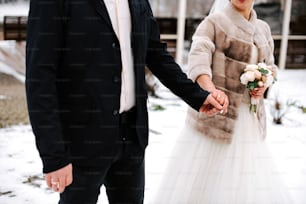 a bride and groom holding hands in the snow
