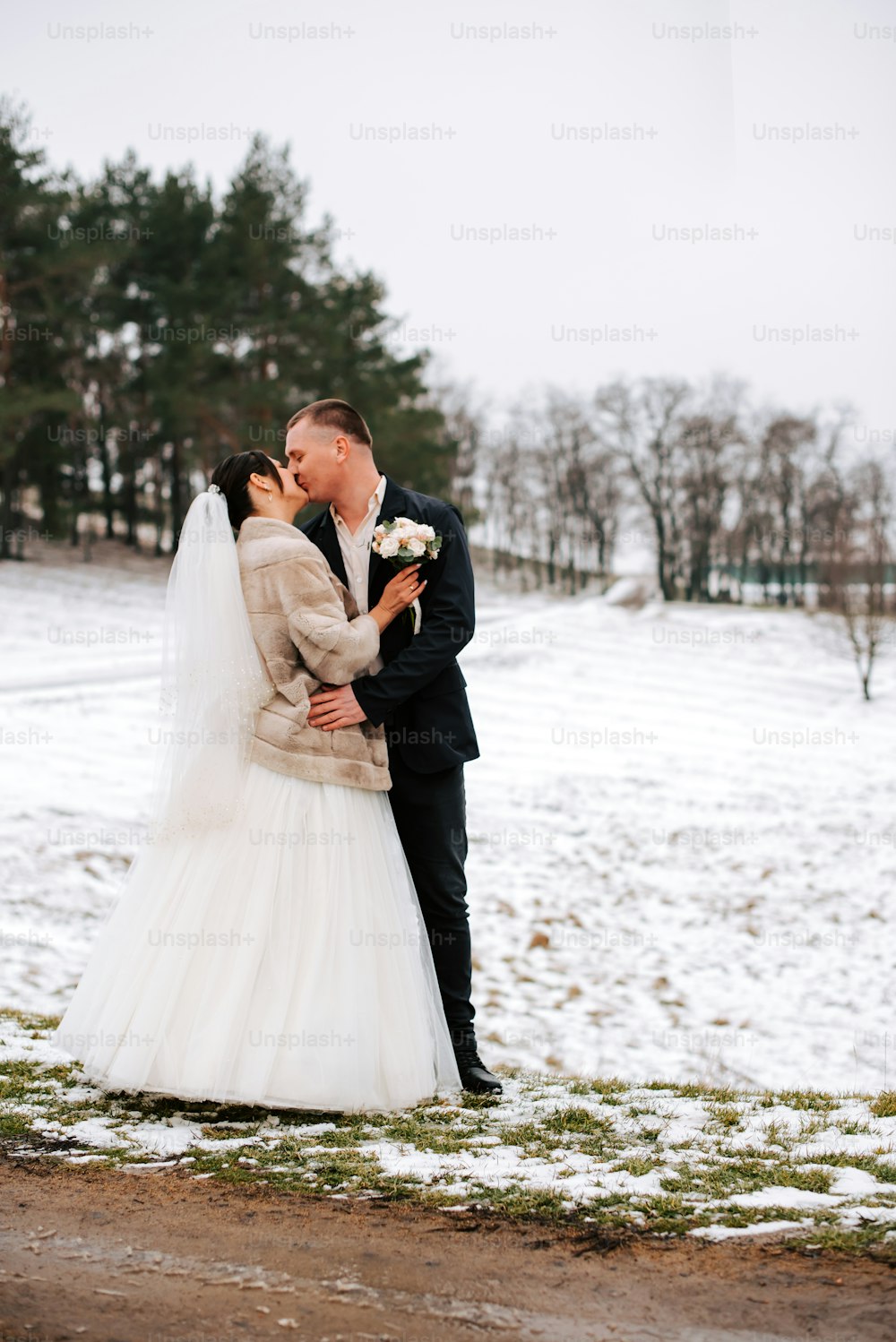 una sposa e uno sposo che si baciano nella neve
