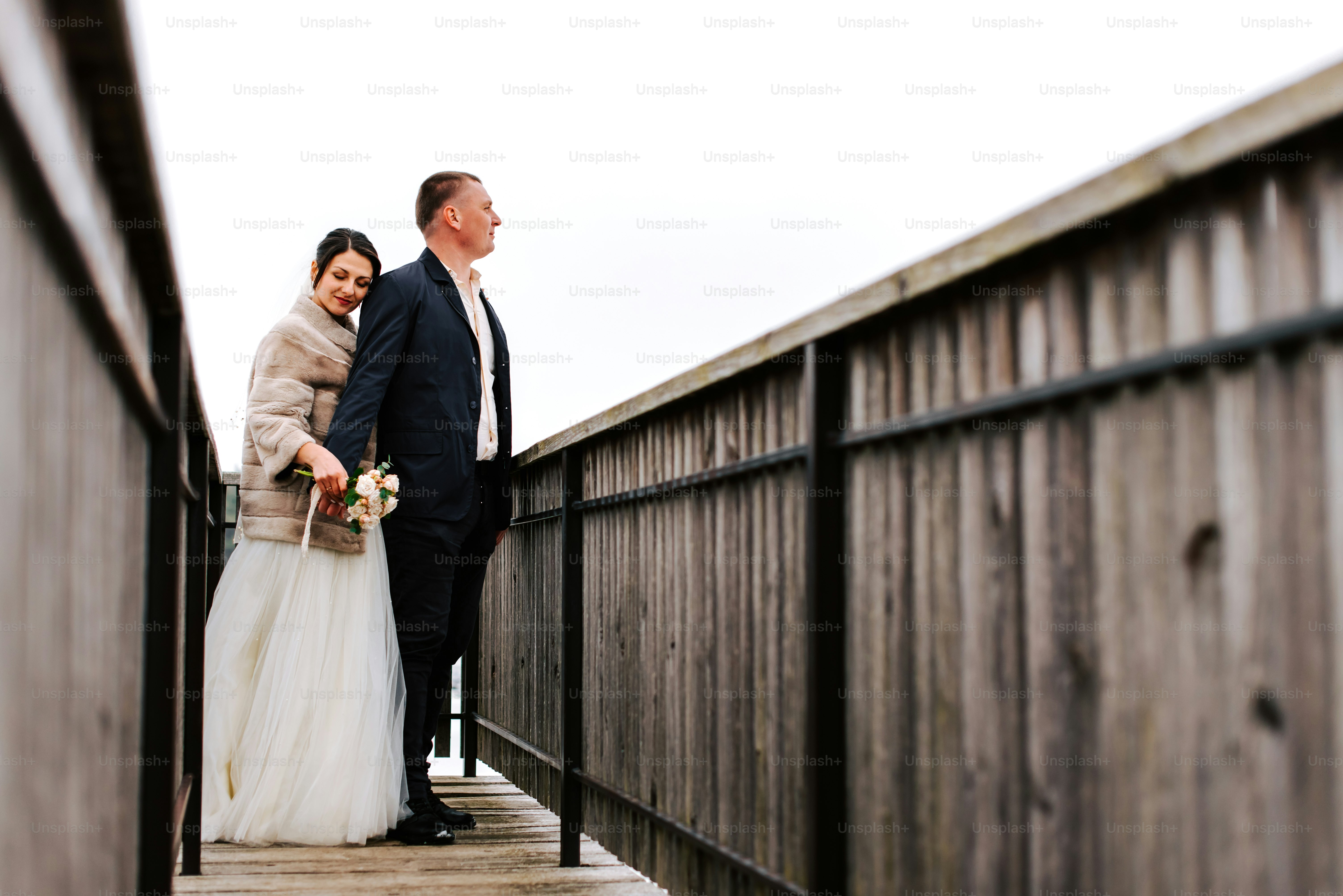 A bride and groom standing on a bridge photo – Bride Image on Unsplash