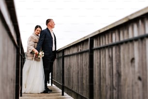 a bride and groom standing on a bridge