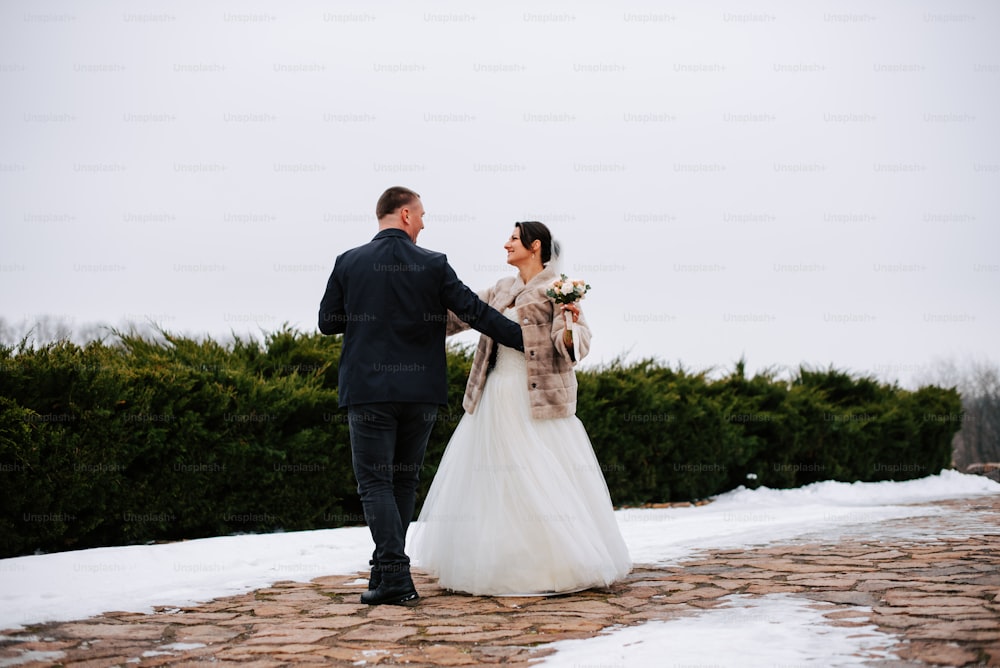 a bride and groom walking in the snow