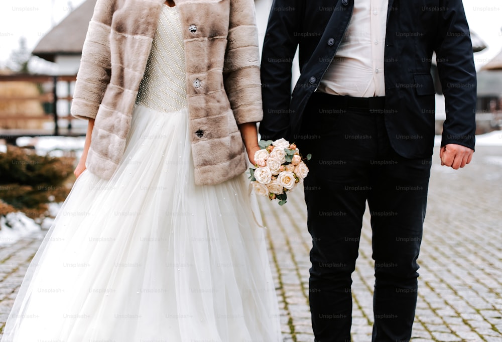 una sposa e uno sposo che si tengono per mano camminando lungo una strada di ciottoli