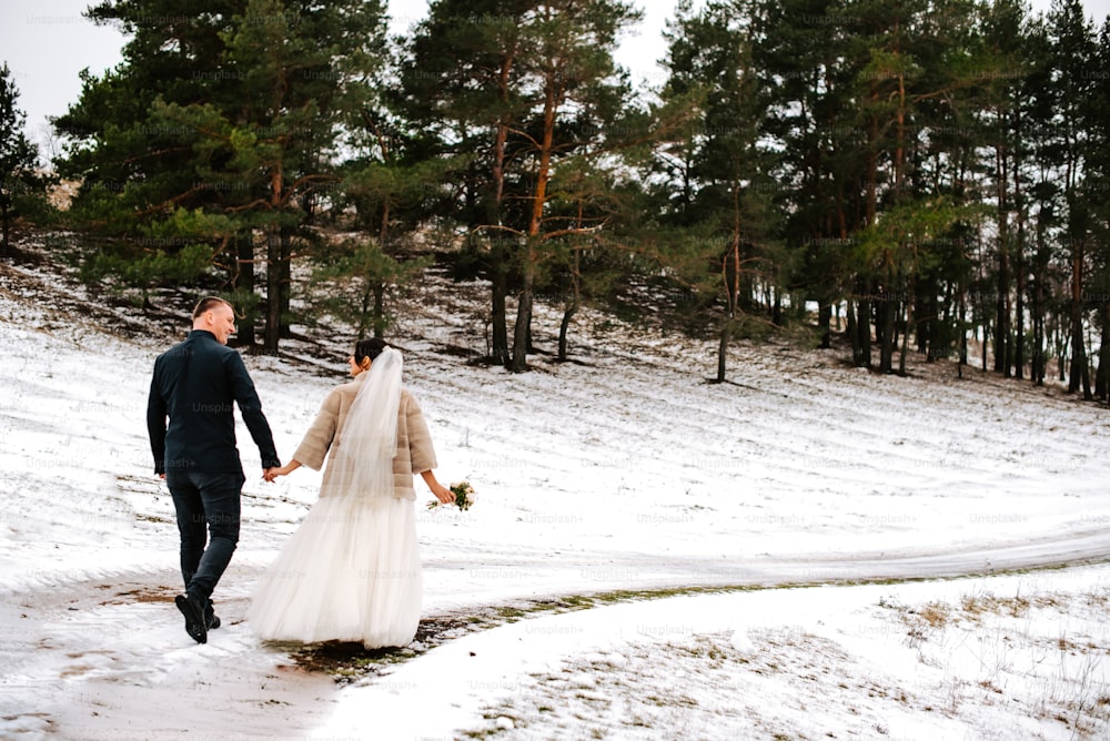 a bride and groom walking in the snow