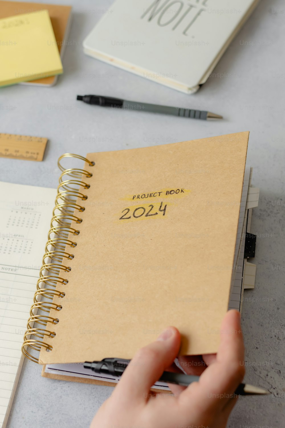 a person holding a pen and a notebook on a table