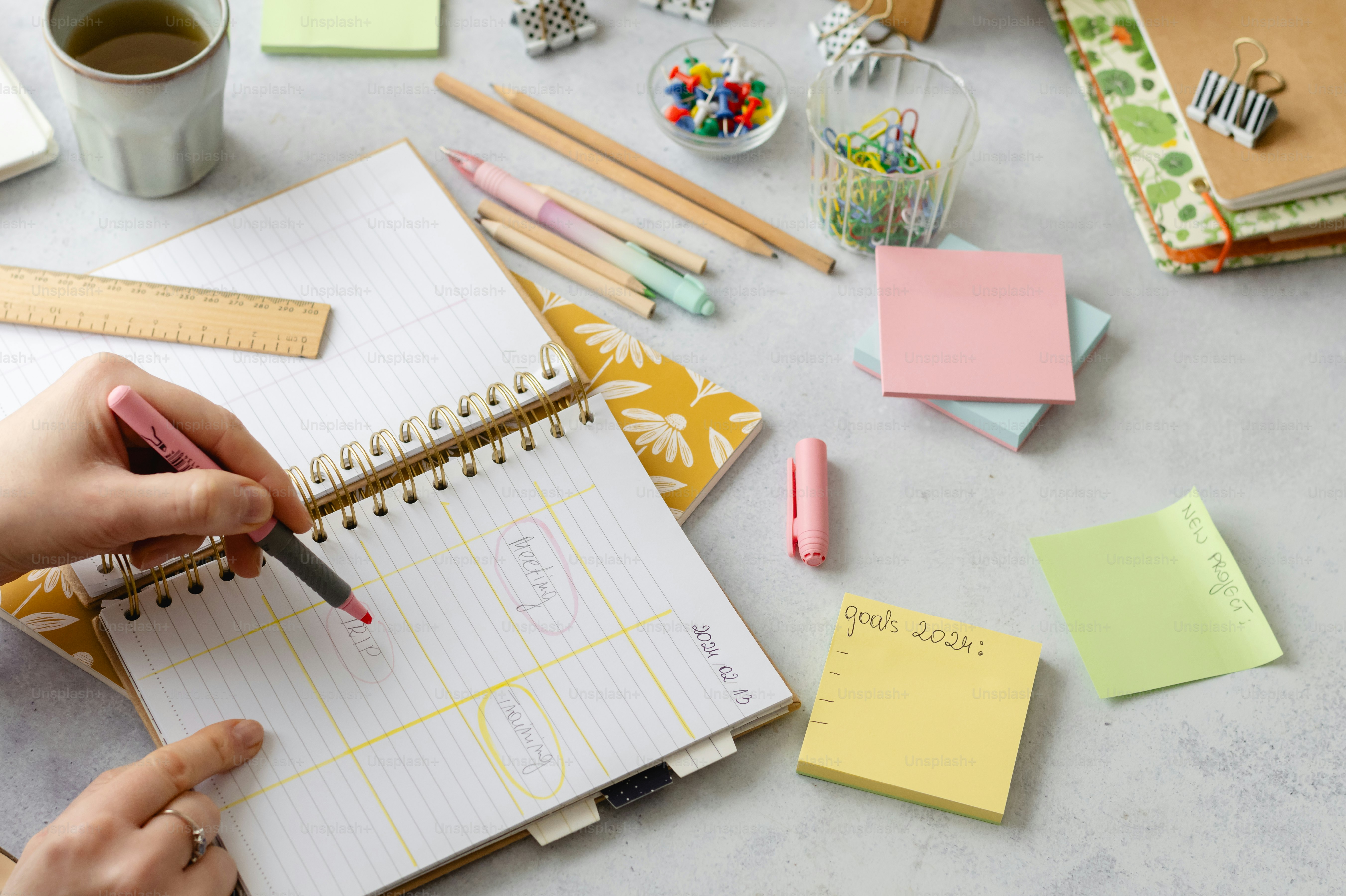 a person writing on a notepad next to a cup of coffee