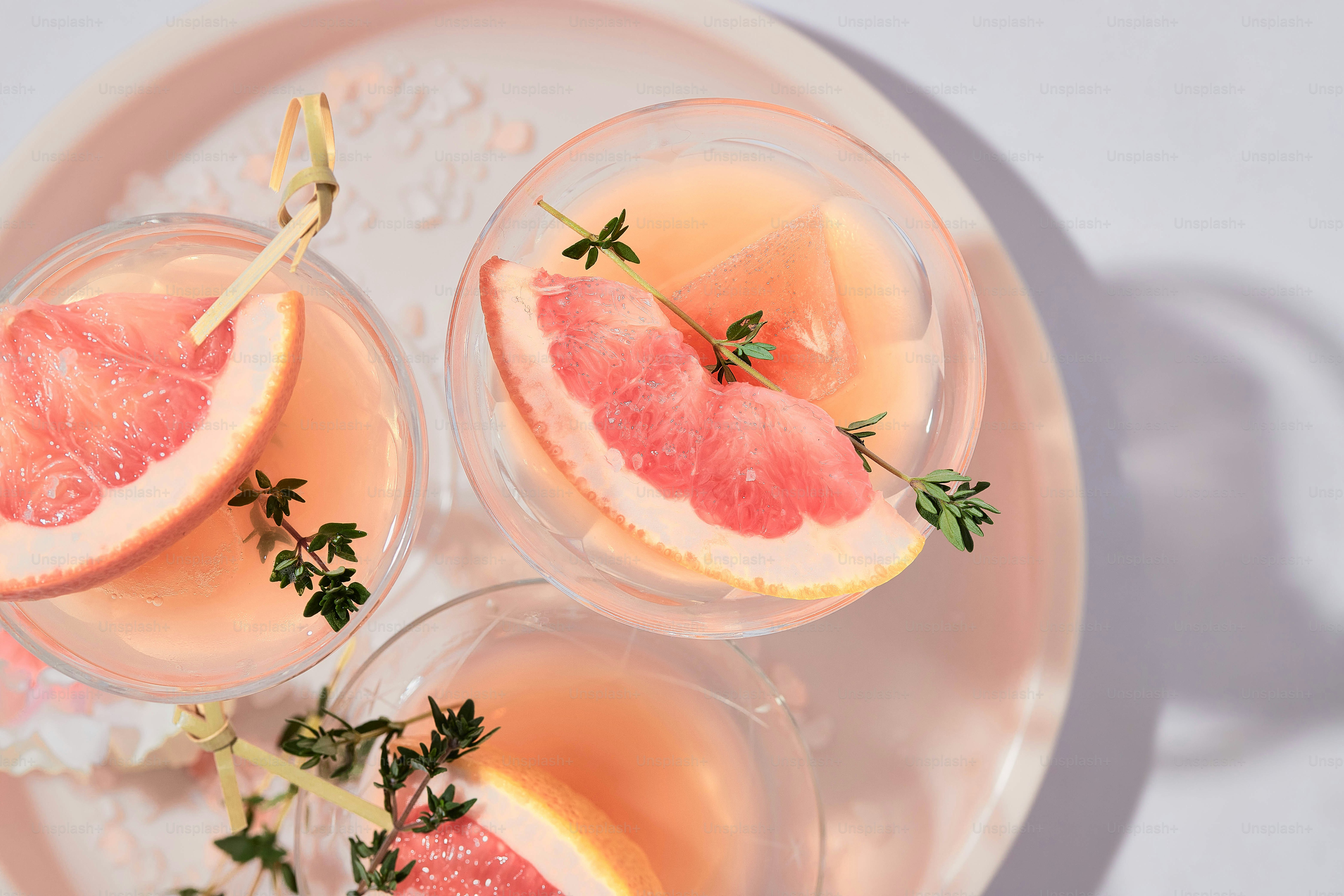 three glasses of wine with grapefruit garnish on a plate