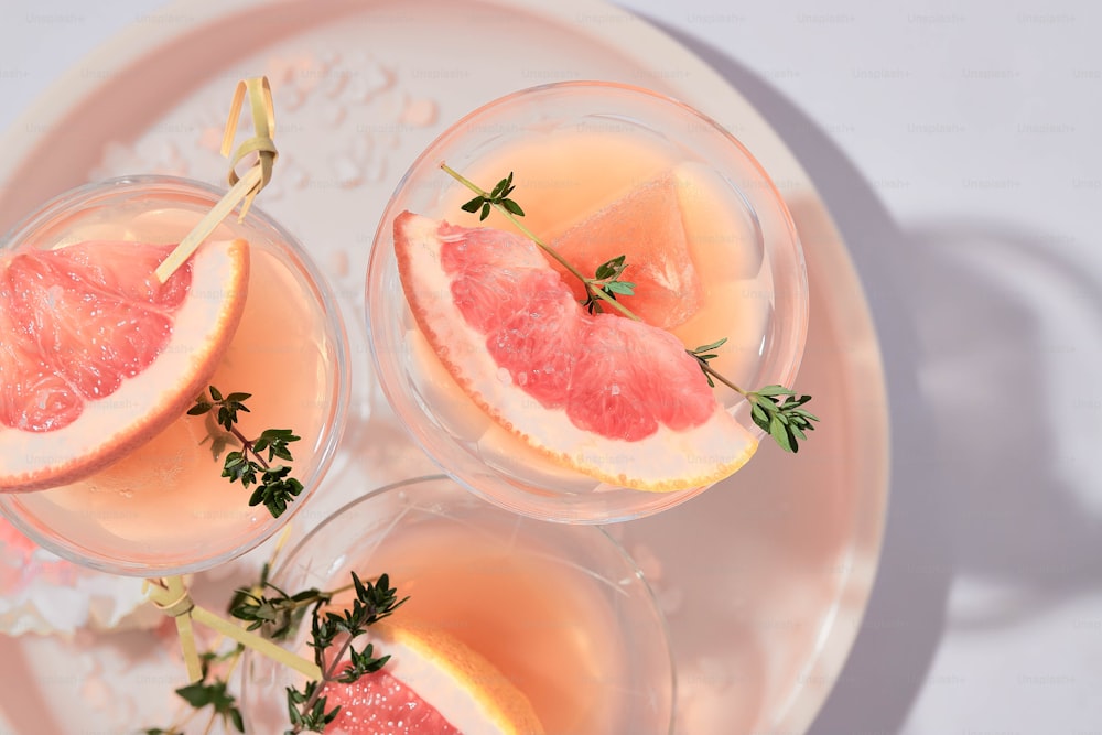 three glasses of wine with grapefruit garnish on a plate