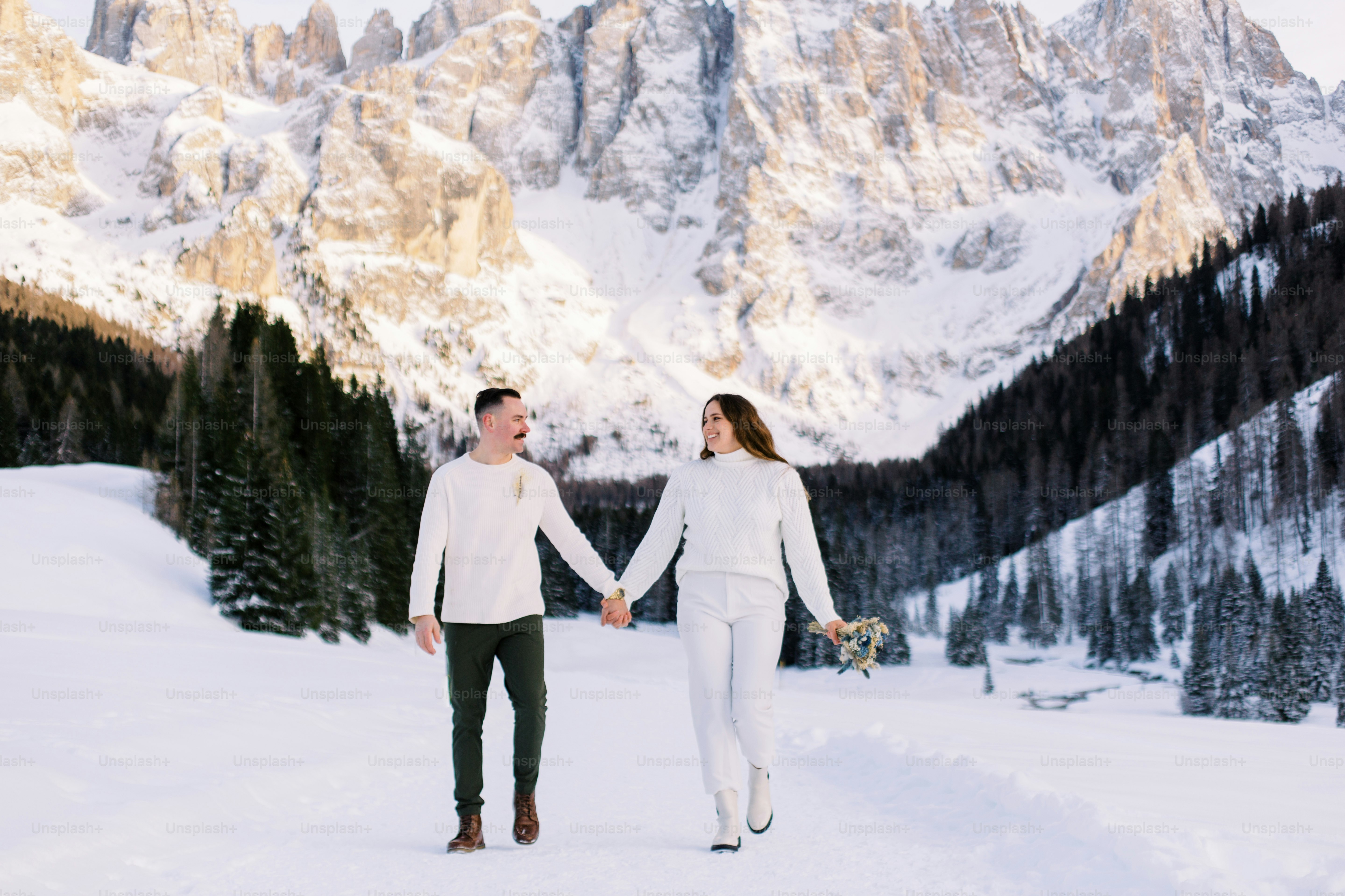 un uomo e una donna che si tengono per mano nella neve