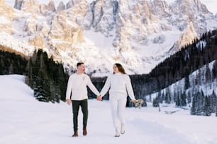 Ein Mann und eine Frau halten Händchen im Schnee