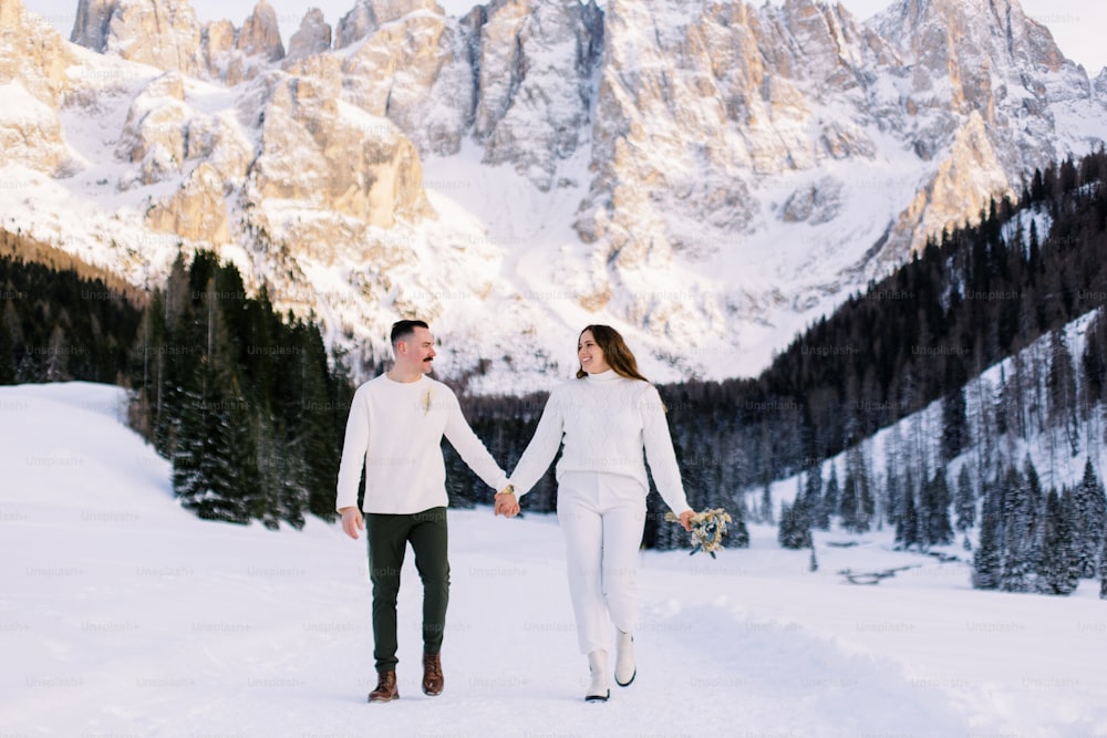 un hombre y una mujer tomados de la mano en la nieve