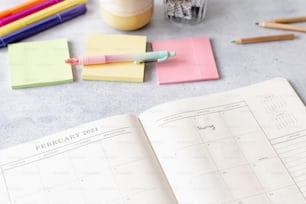 a desk with a calendar, pens, markers and a cup of coffee