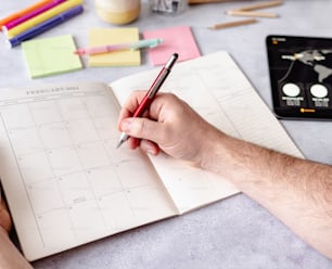 a person holding a pen and writing on a notebook