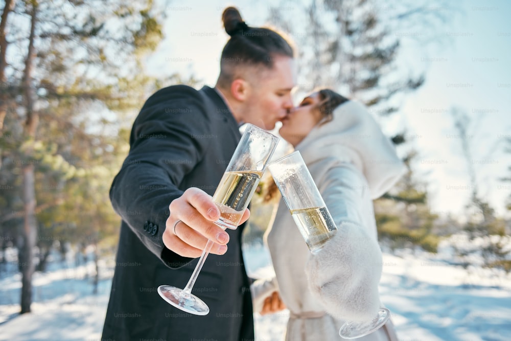 a bride and groom kissing while holding champagne flutes