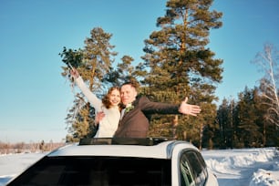 a man and woman standing on top of a car