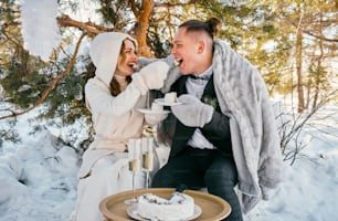 a man and a woman sitting on a bench in the snow