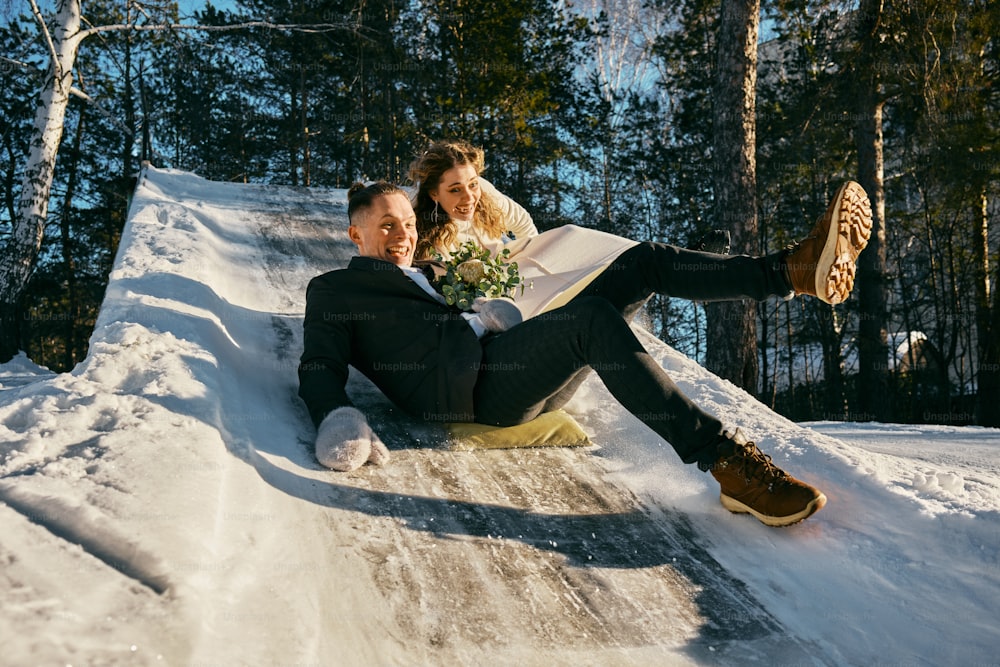 a bride and groom are sitting on a snowy hill