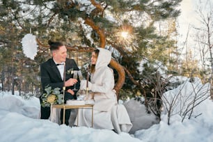 a bride and groom having a toast in the snow