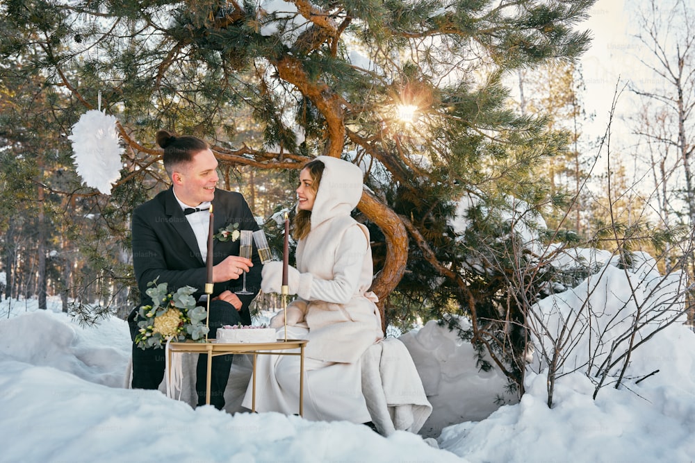 a bride and groom having a toast in the snow