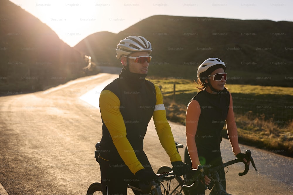 a man and a woman riding bikes down a road