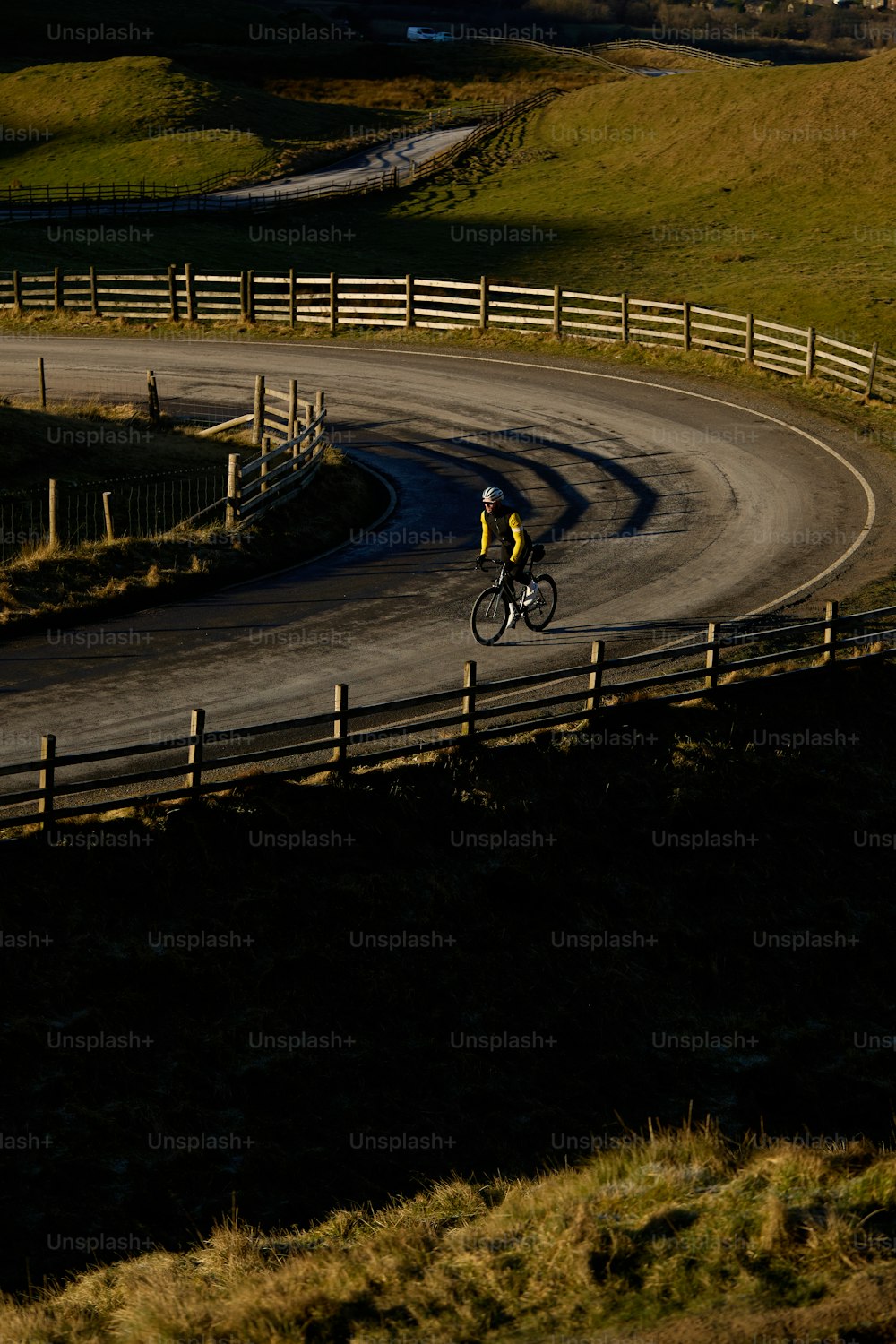 Un hombre montando en bicicleta por una carretera con curvas