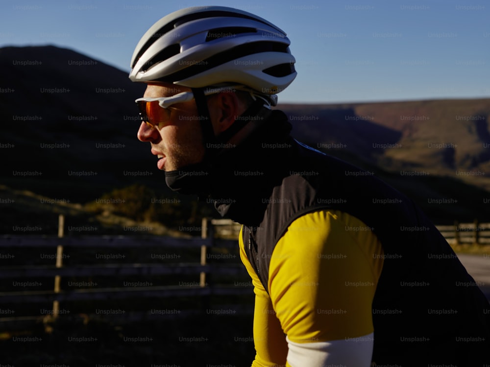 a man riding a bike down a road next to a fence