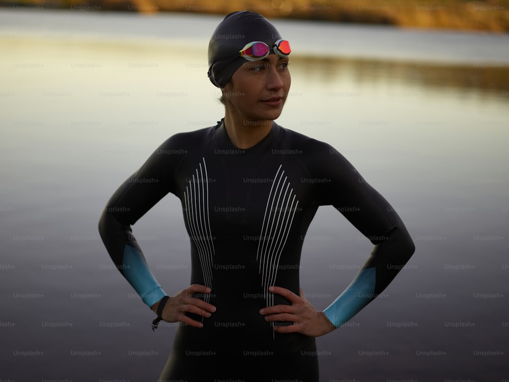 uma mulher de roupa de mergulho e óculos de proteção ao lado de um corpo de água
