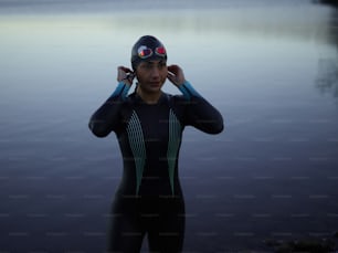 a man in a wet suit standing next to a body of water