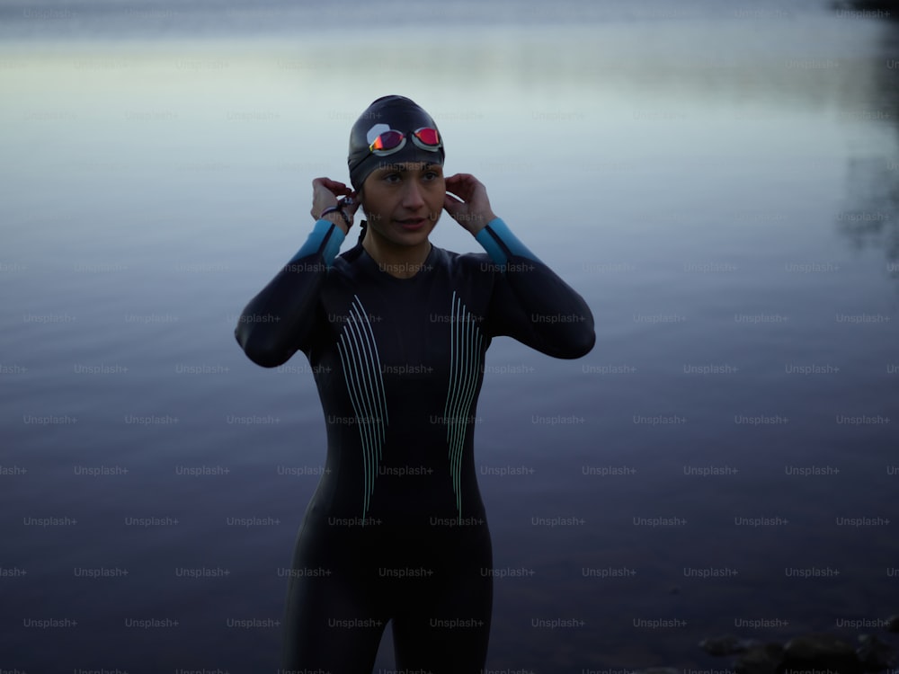 a man in a wet suit standing next to a body of water