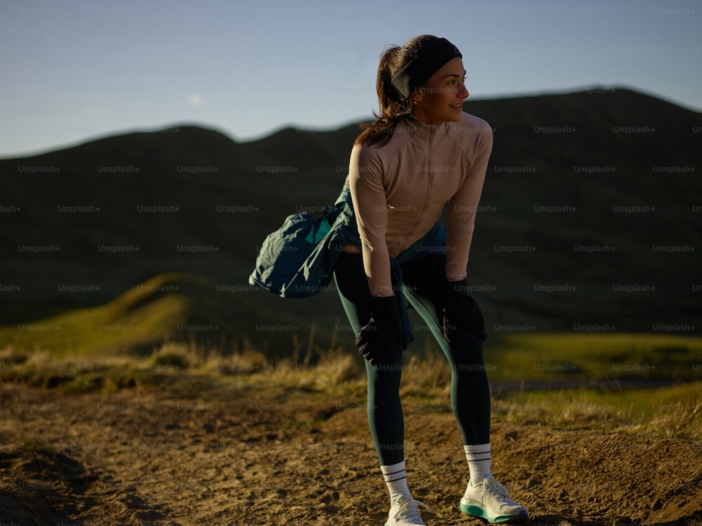 a woman with a backpack standing on a hill