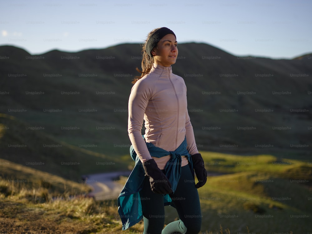 a woman standing on top of a lush green hillside