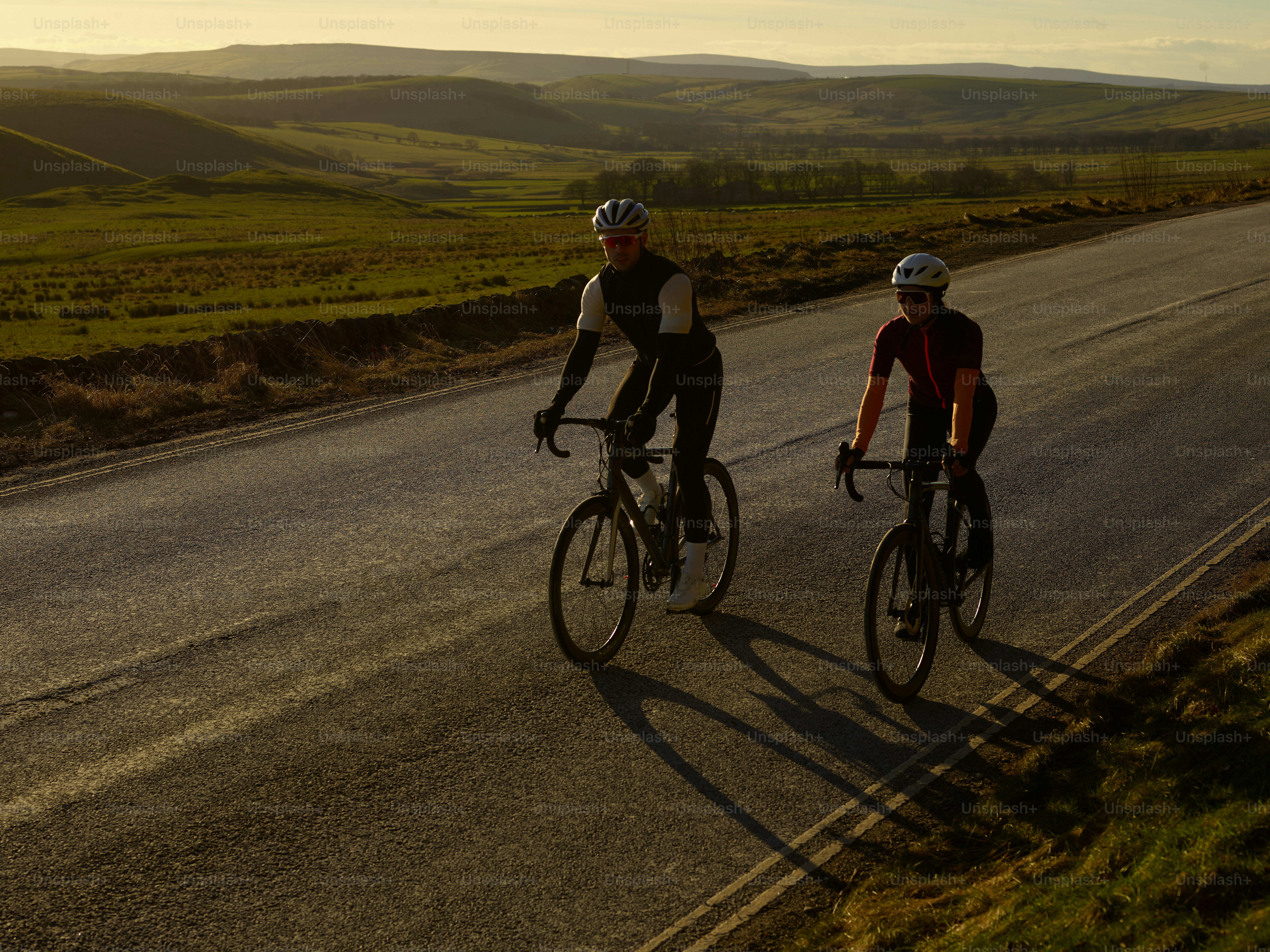 A couple of people riding bikes down a road photo – Outdoor Image on ...