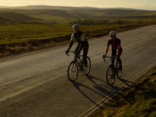 a couple of people riding bikes down a road