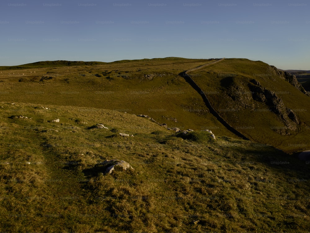 una colina cubierta de hierba con un camino que la atraviesa
