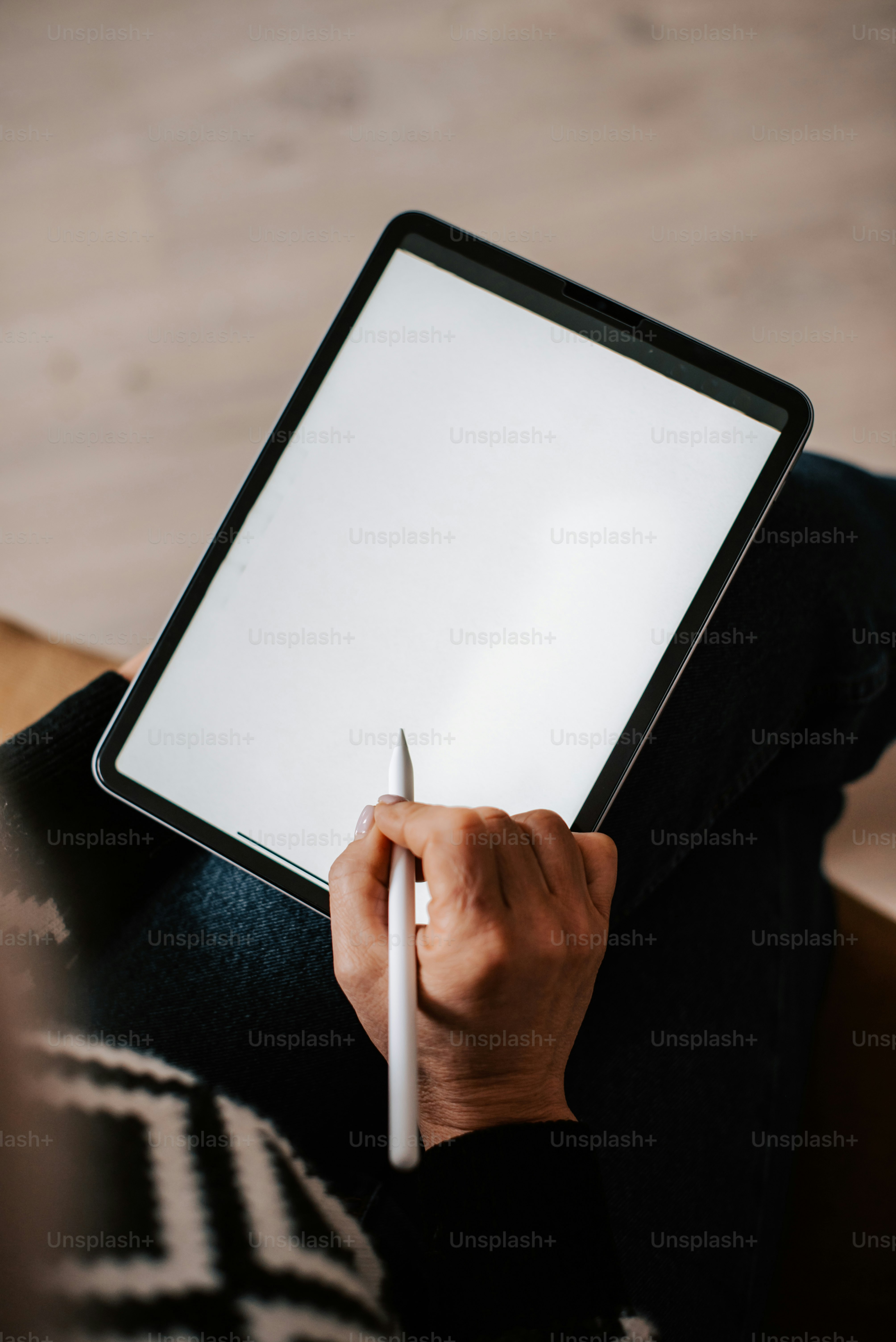 uma pessoa sentada em um sofá escrevendo em um tablet