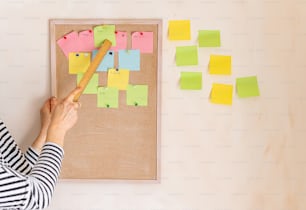 a woman is putting post it notes on a bulletin board