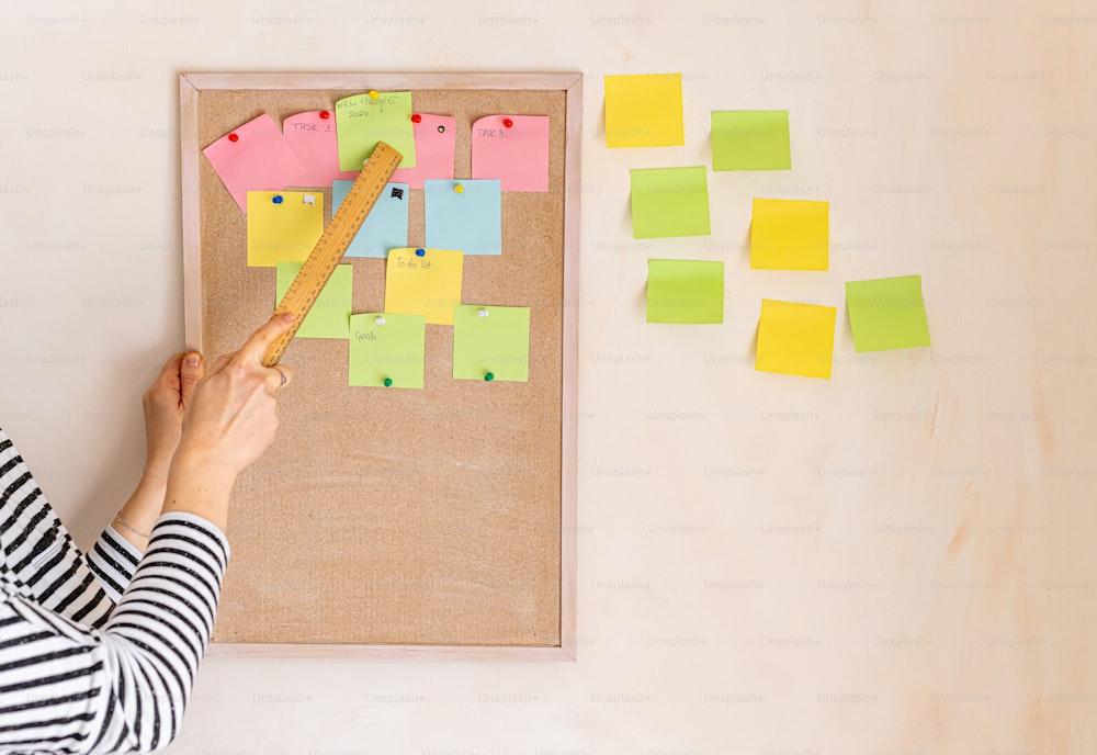 a woman is putting post it notes on a bulletin board