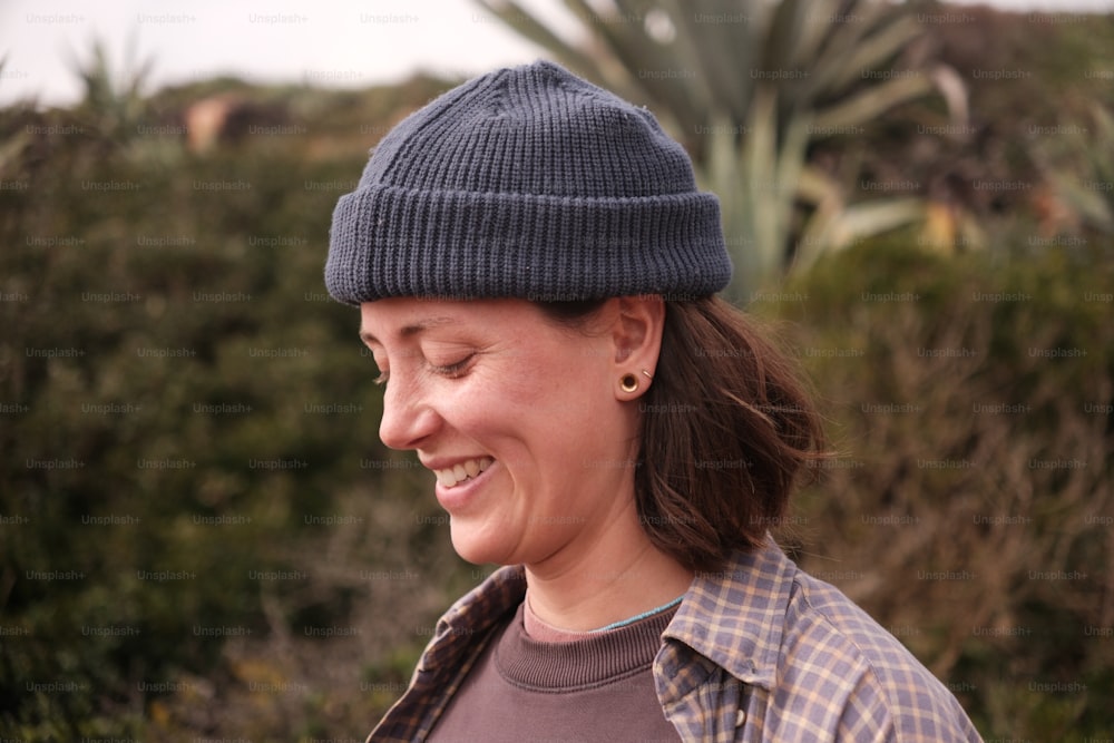 a woman wearing a blue beanie smiles at the camera