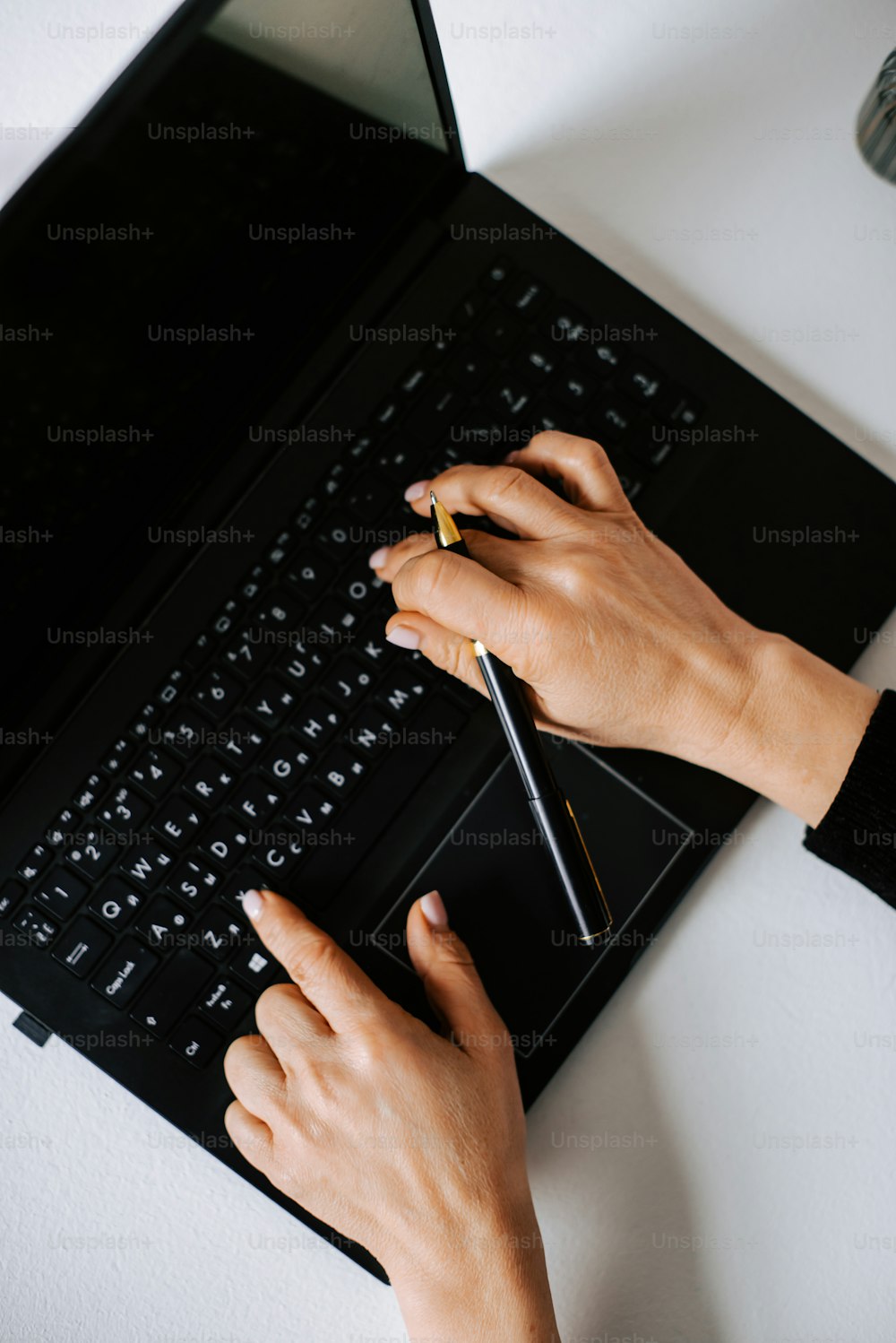 a person is writing on a black laptop