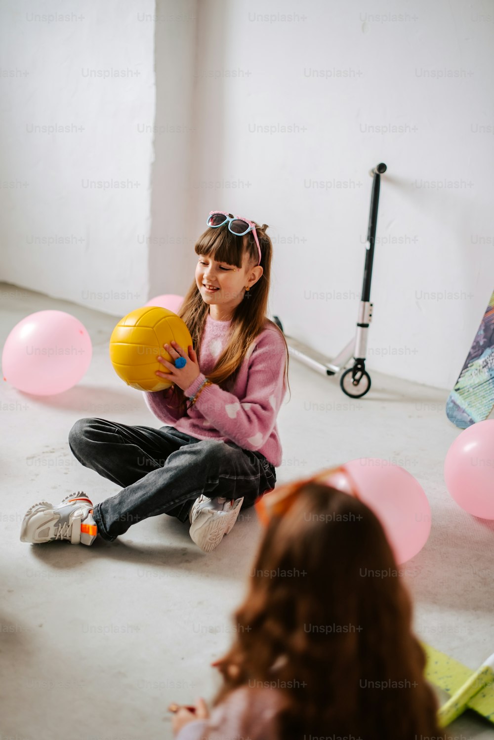 a young girl sitting on the floor holding a ball