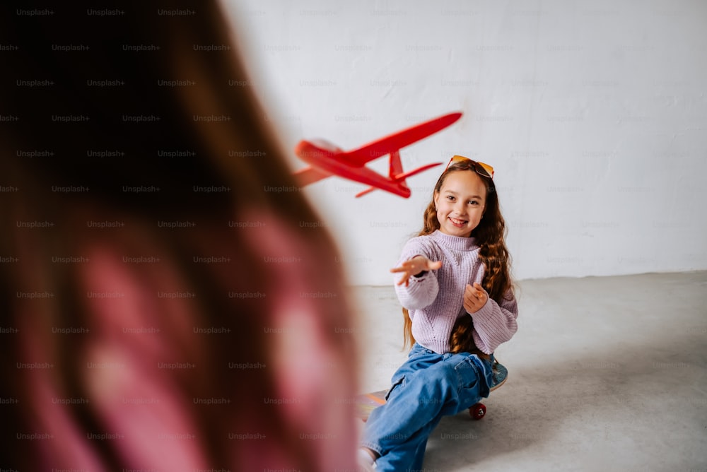 a little girl sitting on the floor with a toy airplane