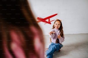 una niña sentada en el suelo con un avión de juguete