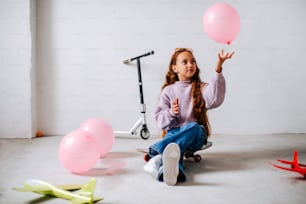 a little girl sitting on the floor with balloons