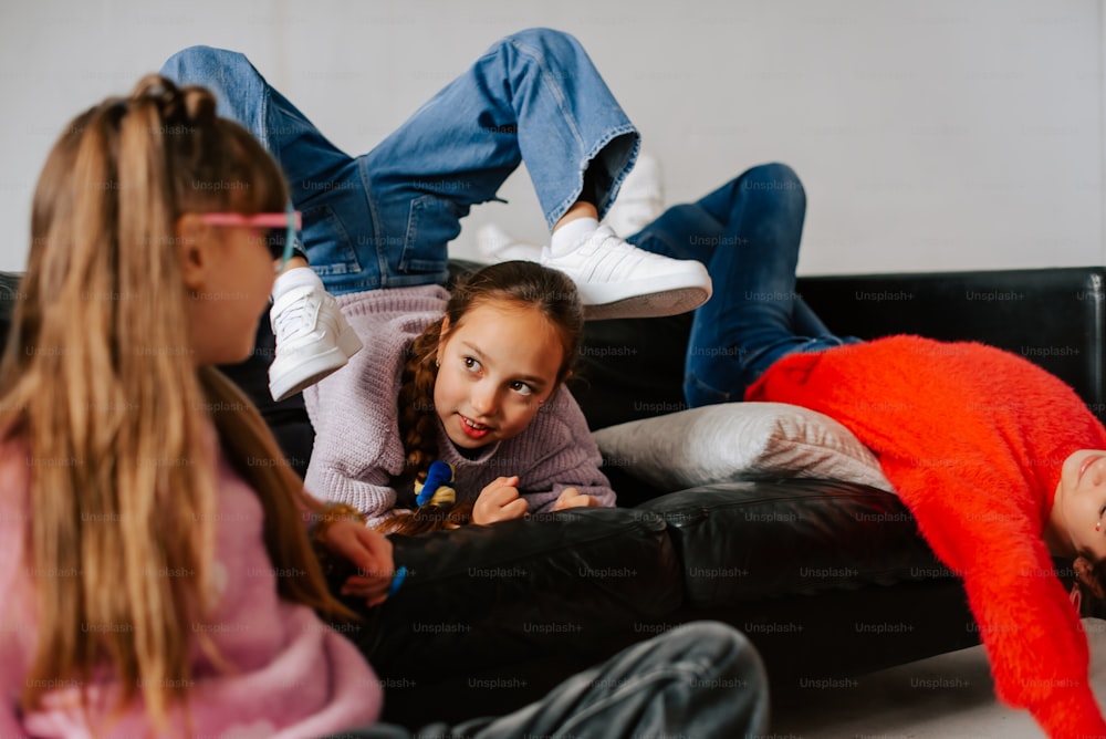 a group of young girls sitting on top of a black couch