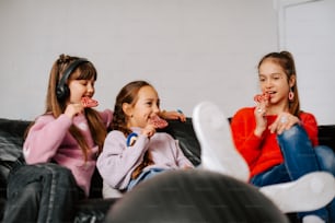 three girls sitting on a couch eating candy