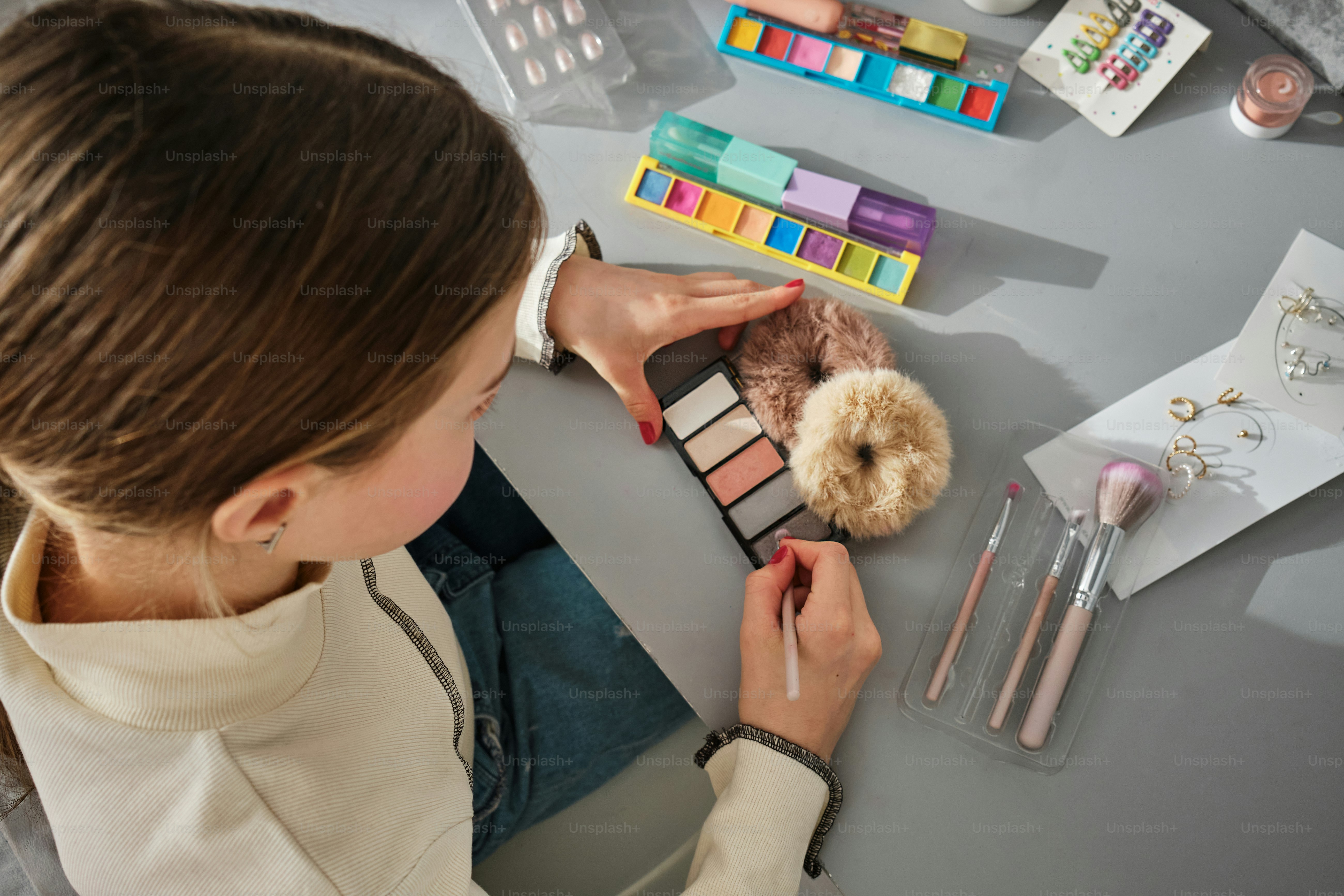 eine Frau, die mit Make-up und einem Teddybären an einem Tisch sitzt